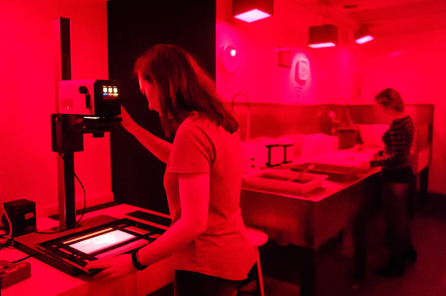 Photography darkroom Students processing film photographs in darkroom, lit red